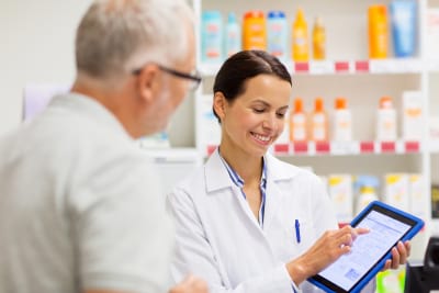 happy apothecary and senior customer with tablet pc computer at pharmacy